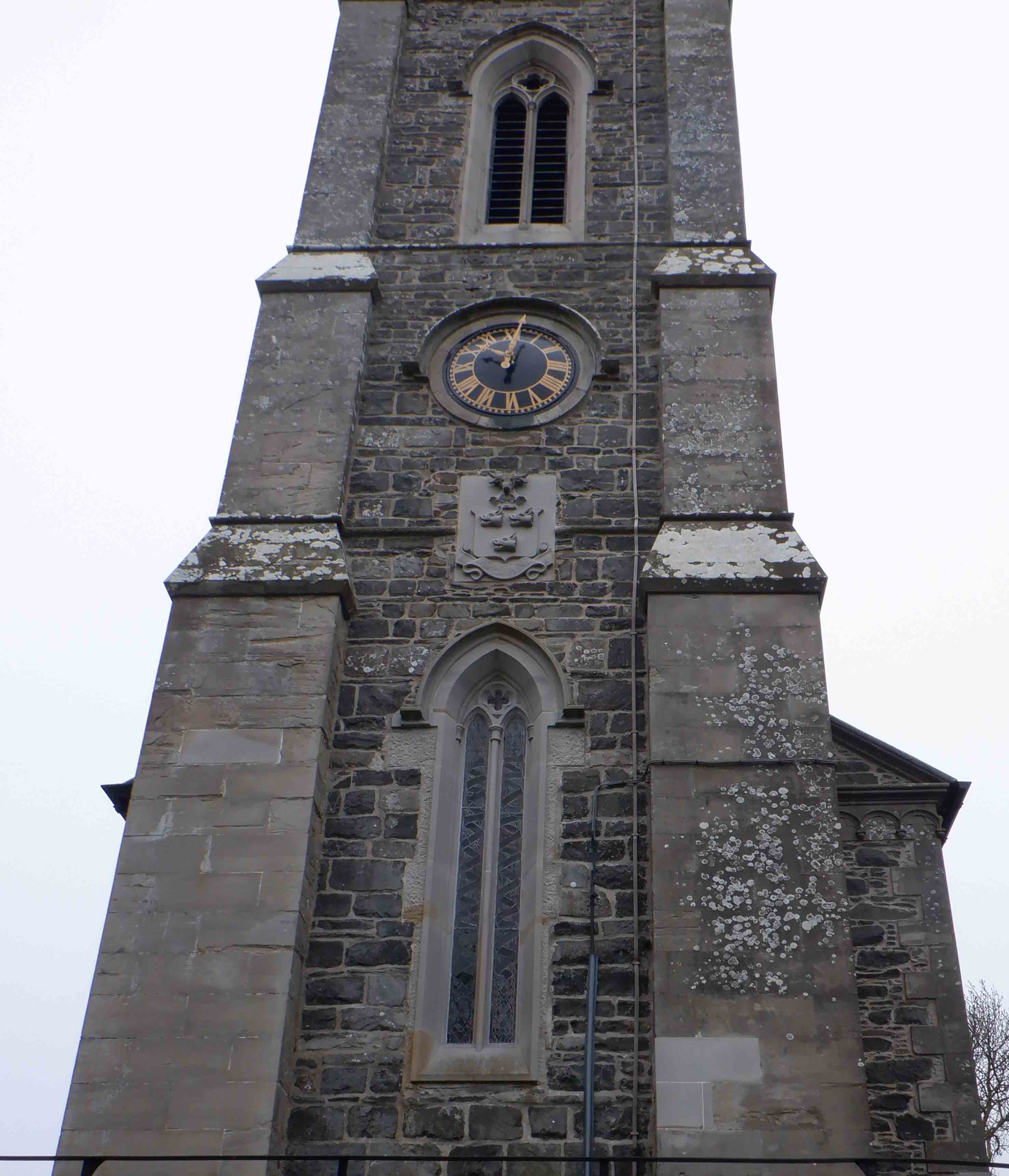 What animals are below the west facing clock on the spire of Kilmood church?