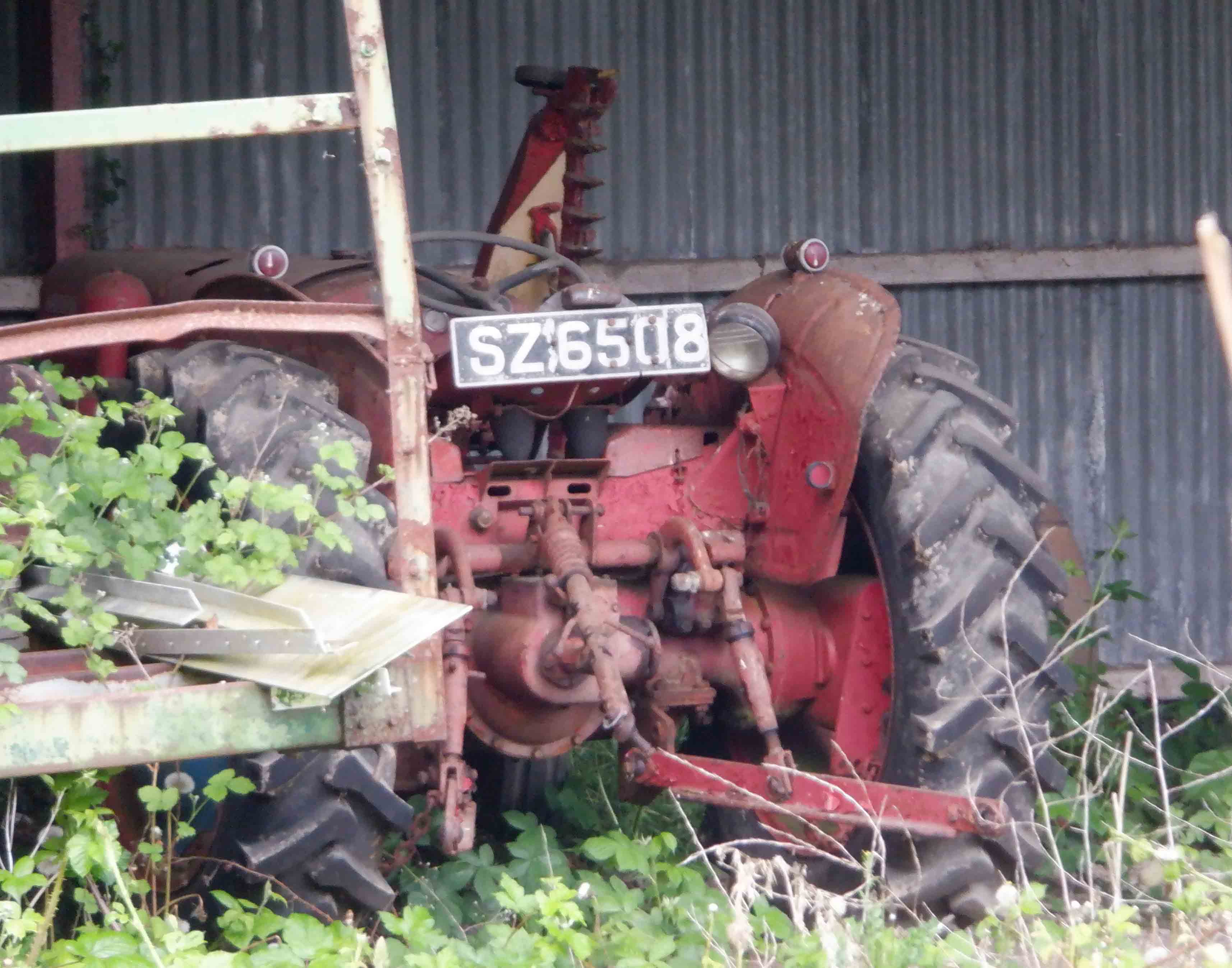 What is the number plate of the old tractor in the barn opposite no. 20?
